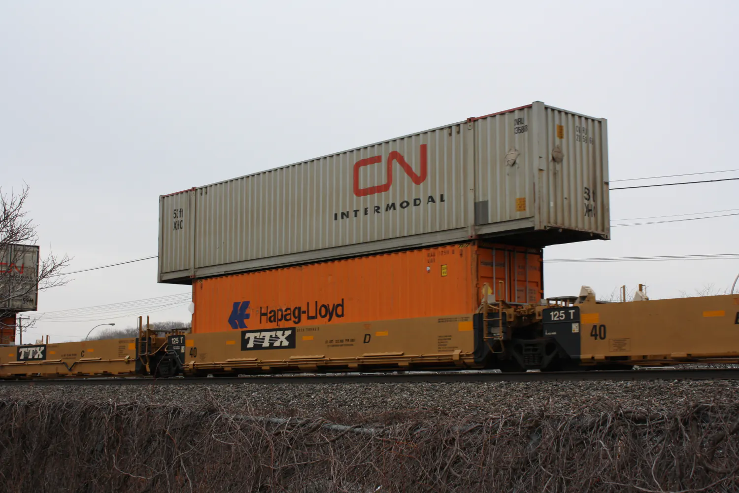 Double-stacked CN Intermodal and Hapag-Lloyd shipping containers riding a TTX well car on a Canadian National freight train
