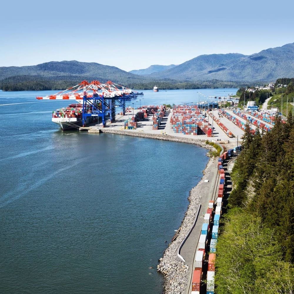 Fairview Container Terminal at the Port of Prince Rupert with an on-dock unit train along the shoreline, surrounded by coastal mountains